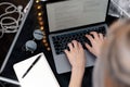 Female hand using touchpad of laptop. Black desk with sunglasses, pen and notebook. Royalty Free Stock Photo
