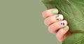 Female hand with vacation nail design. Glitter green nail polish manicure. Female model hand with perfect green manicure