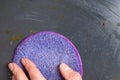 A female hand washes brown stains on a black plate, frying pan, dishes with a lilac sponge, close-up, top view Royalty Free Stock Photo