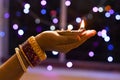 Woman holds lit earthen diwali lamp in one hand