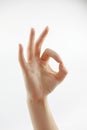 Female hand on white background with shadow. The thumb and forefinger are assembled into round O or OK