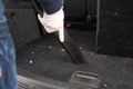 Female hand in white gloves hoovering a car cabin