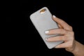 Female hand with white manicure close-up holding mobile phone grey smartphone on black background Royalty Free Stock Photo