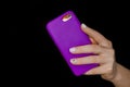 Female hand with white manicure close-up holding mobile phone lilac purple smartphone on black background Royalty Free Stock Photo