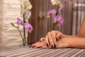 Female hand with wine color nails polish on a desk in beauty studio and blurred floral background Royalty Free Stock Photo