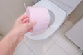 A female hand, woman holding a roll of pink toilet paper, digestive problems and defecation disorder concept