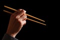 Female hand with wooden chopsticks. Hand holding traditional sushi bamboo sticks for Chinese, Japanese, Thai or Asian food