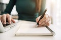 Female hand working at a computer and writing on a notepad. Royalty Free Stock Photo