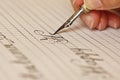 Female hand writes with the inky pen on a white paper sheet with stripes. stationery on desk close up top view. spelling lessons Royalty Free Stock Photo