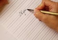 Female hand writes with the inky pen the word hope on a white paper sheet with stripes. stationery on desk close up top view. Royalty Free Stock Photo