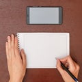 Female hand writes a pen in a notebook on the table next to the smartphone Royalty Free Stock Photo