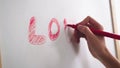 Female hand writes the word LOVE with a marker on a white board