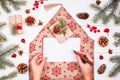 Female hand writing a letter to Santa on holiday background with Christmas gifts, Fir branches, pine cones, red decorations Royalty Free Stock Photo