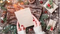 Female hand writing a letter to Santa on wooden background with Christmas gifts, bark texture, Fir branches, pine cones, red decor Royalty Free Stock Photo