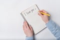 Female hand writing in notebook the words I LOVE YOU. Top view of notebook and hands. White background Royalty Free Stock Photo