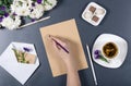 Female hand writing on a sheet of brown craft paper. Fresh chrysanthemums, pencils, envelope with note and flower, cup of tea on Royalty Free Stock Photo