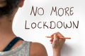 Female hand writting the phrase No More Lockdown on a white paper, indoors. Lockdown financial and social crisis concept