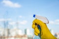 Female hand in yellow gloves cleaning window with spray detergent. Spring cleanup Royalty Free Stock Photo