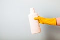 a female hand in a yellow rubber glove holds a white bottle of bleach for clothes Royalty Free Stock Photo