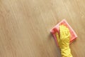 Female hand in a yellow rubber glove washes a wooden parquet floor with a pink microfiber cloth. Royalty Free Stock Photo