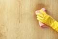 A female hand in a yellow rubber glove wipes a stain of dirt on the wooden parquet floor with a pink microfiber cloth. Royalty Free Stock Photo