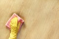 A female hand in a yellow rubber glove wipes a stain of dirt on the wooden parquet floor with a pink microfiber cloth. Royalty Free Stock Photo