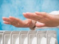 Female hands above the heater