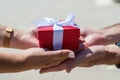 Female hands accept a gift from male hands. on the street they give a red box, a white bow. holiday concept, surprise Royalty Free Stock Photo