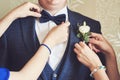 female hands adjust the groom's bow tie and boutonniere. preparing the groom morning hands close-up