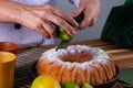 female hands applying lemon zest with grater on lemon cake