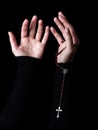 Female hands with arms outstretched praying and holding rosary with cross or Crucifix.