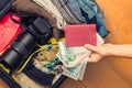 Female hands with Asian money and foreign passport. Suitcase with things on the floor.Travel concept Royalty Free Stock Photo
