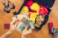 Female hands with Asian money and foreign passport. Suitcase with things on the floor. Travel concept Royalty Free Stock Photo