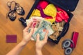 Female hands with Asian money and foreign passport. Suitcase with things on the floor.Travel concept Royalty Free Stock Photo