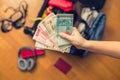 Female hands with Asian money and foreign passport. Suitcase with things on the floor.Travel concept Royalty Free Stock Photo