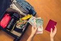 Female hands with Asian money and foreign passport. Suitcase with things on the floor.Travel concept Royalty Free Stock Photo