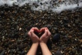 female hands depict a heart on the background of wet pebbles Royalty Free Stock Photo