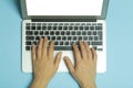 Female hands behind a laptop. Female hands work on a computer keyboard on the Internet on a blue background of the Royalty Free Stock Photo