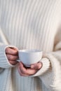 Female hands in beige sweater holding cup with hot drink Royalty Free Stock Photo