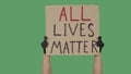 Female hands in black gloves pick up a poster from a cardboard box that reads ALL LIVES MATTER. Struggle for equality Royalty Free Stock Photo