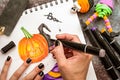 Female hands with black nails drawing halloween illustration with markers on wooden table top view Royalty Free Stock Photo
