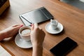 Female hands with a black phone, close-up, background of a cup of coffee, table, notebook. Business lunch Royalty Free Stock Photo