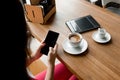 Female hands with a black phone, close-up, background of a cup of coffee, table, notebook. Business lunch Royalty Free Stock Photo