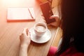 Female hands with a black phone, close-up, background of a cup of coffee, table, notebook. Business lunch Royalty Free Stock Photo