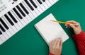 Female hands, blank notepad and music keys on a green background, top view. Royalty Free Stock Photo