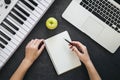 Female hands, blank notepad, piano and laptop on a black background, top view. Royalty Free Stock Photo
