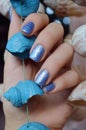 Female hands with blue glitter nail design.