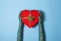 Female hands in blue retro gloves holding Red Heart shaped gift box with gold bow over blue background. Top view. Valentine`s Day Royalty Free Stock Photo