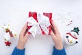 Female hands in a blue sweater are holding a red box with a Christmas present and cute Christmas toys