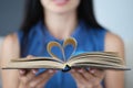 In female hands, book sheets are folded in shape of heart closeup Royalty Free Stock Photo